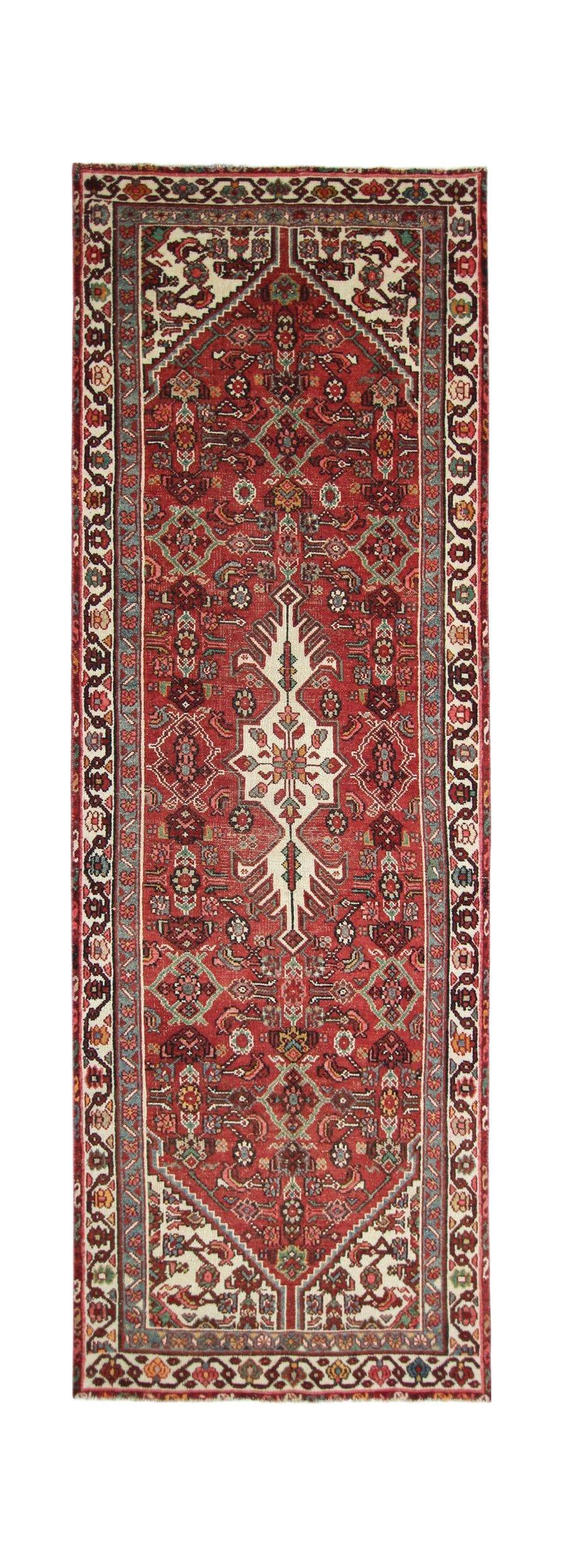 A handmade vintage Persian runner featuring a central geometric medallion on a red wool field.