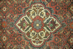 A vintage Persian runner featuring a central floral medallion in a geometric, multi-colored pattern.