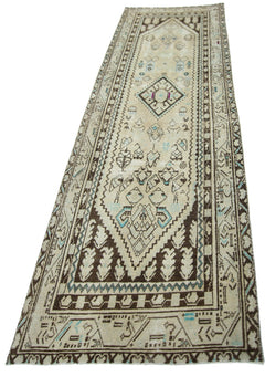 A vintage Persian runner rug featuring geometric patterns in brown, cream, and light blue.