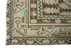A corner detail of a vintage Persian runner featuring geometric brown patterns on a cream background.