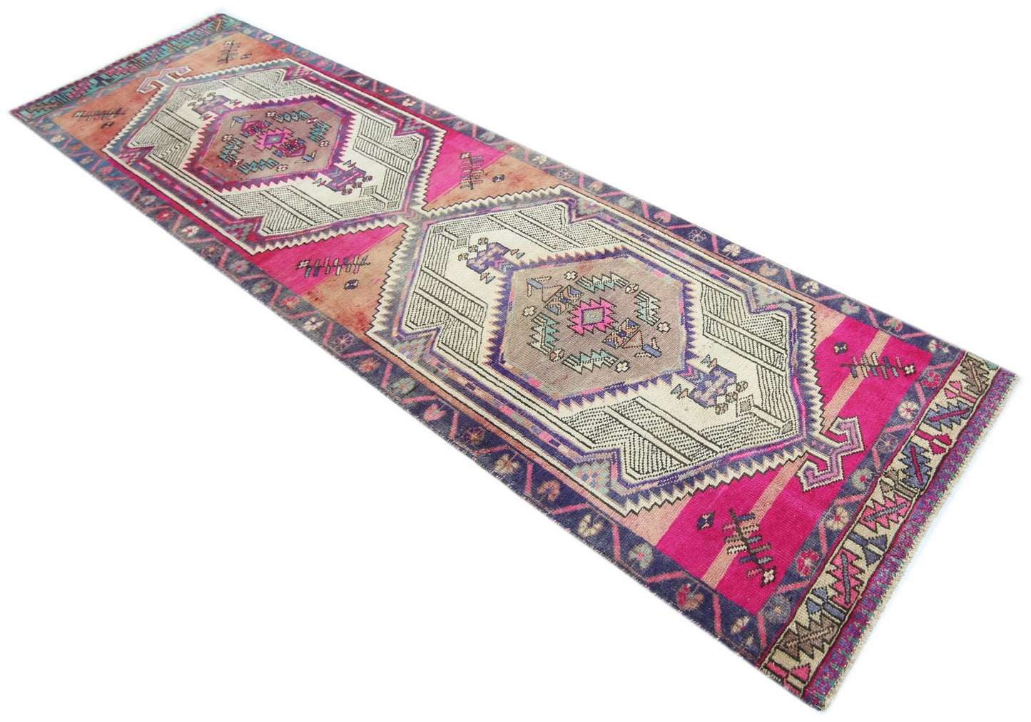 A vintage Persian runner rug featuring two large geometric medallions on a vibrant pink background.