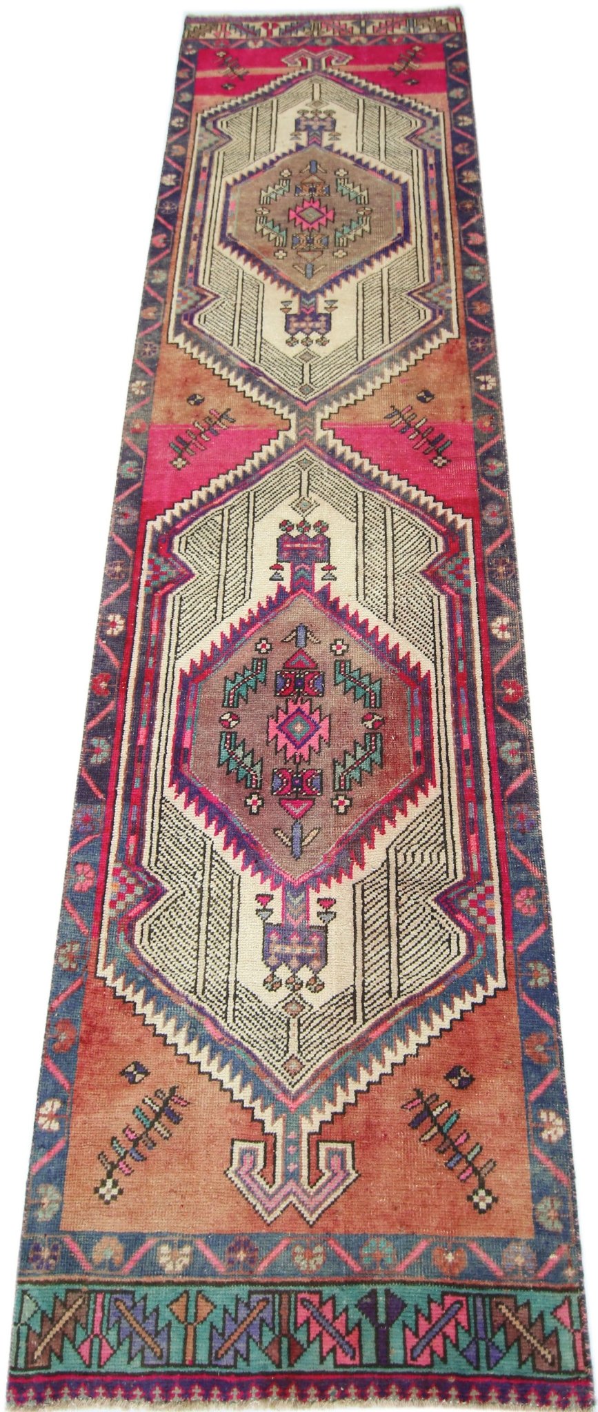 A handmade vintage Persian runner featuring geometric medallions in vibrant pink, orange, and blue.