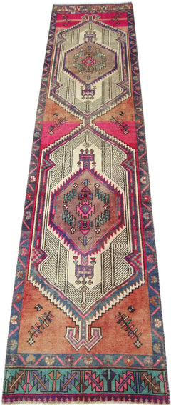 A handmade vintage Persian runner featuring geometric medallions in vibrant pink, orange, and blue.
