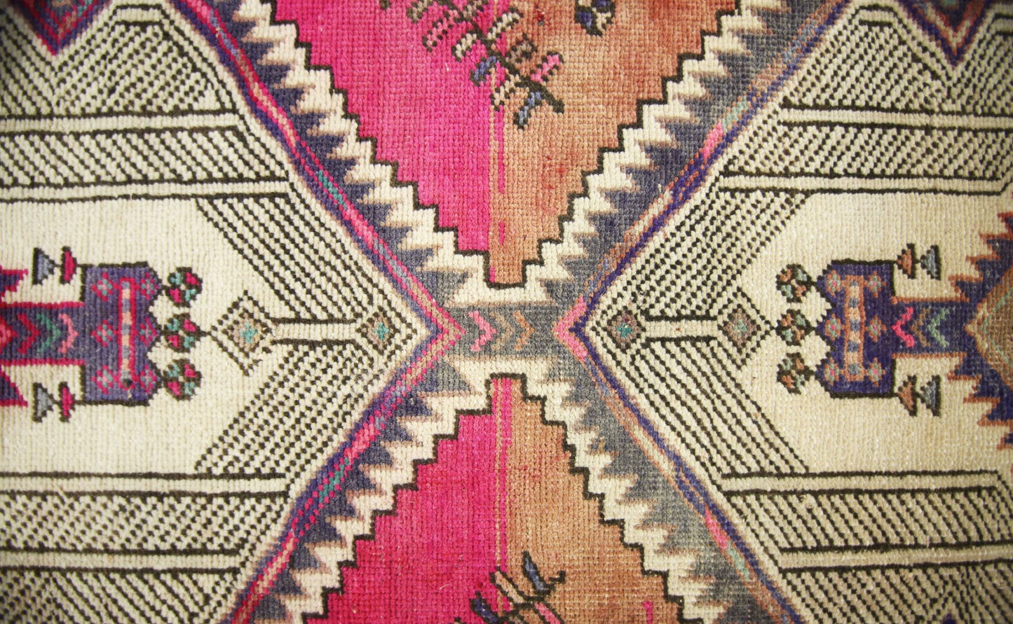 A vintage Persian runner featuring a geometric diamond pattern in vibrant pink, orange, and blue.