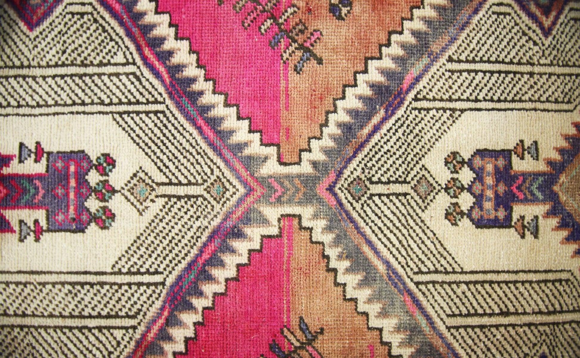 A vintage Persian runner featuring a geometric diamond pattern in vibrant pink, orange, and blue.