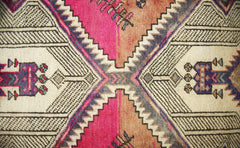 A vintage Persian runner featuring a geometric diamond pattern in vibrant pink, orange, and blue.