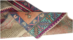 A vintage Persian runner with a folded corner revealing intricate geometric patterns and colors.