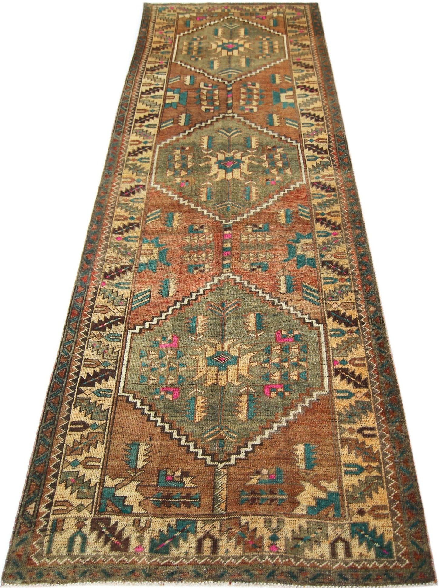 A vintage handmade Persian runner rug featuring geometric diamond medallions in earthy tones.