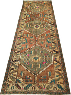 A vintage handmade Persian runner rug featuring geometric diamond medallions in earthy tones.