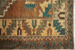 A close-up of a vintage Persian runner featuring geometric patterns in teal, brown, and tan wool.