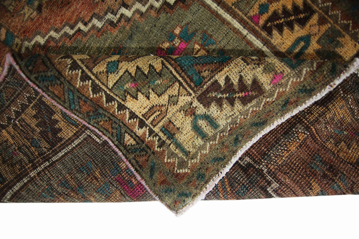 A folded vintage Persian runner featuring intricate geometric patterns in earthy tones.