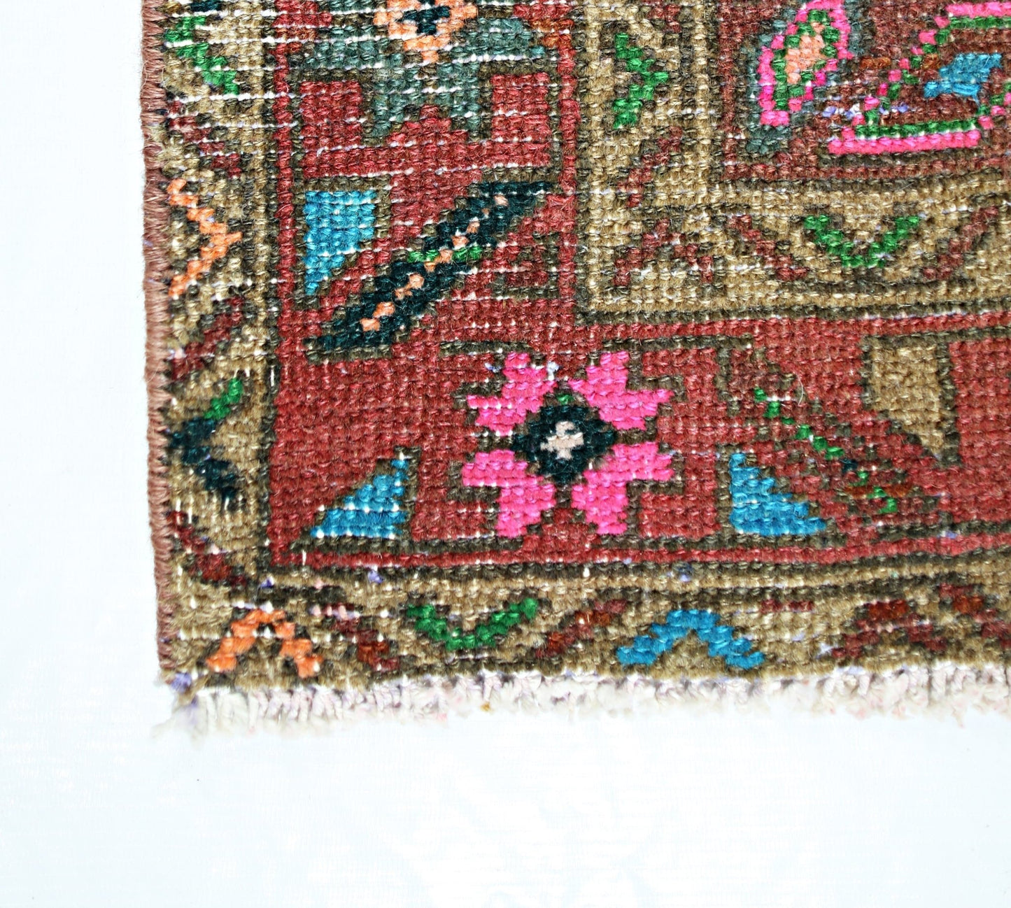 A close-up of a vintage Persian runner featuring a geometric floral pattern in vibrant colors.