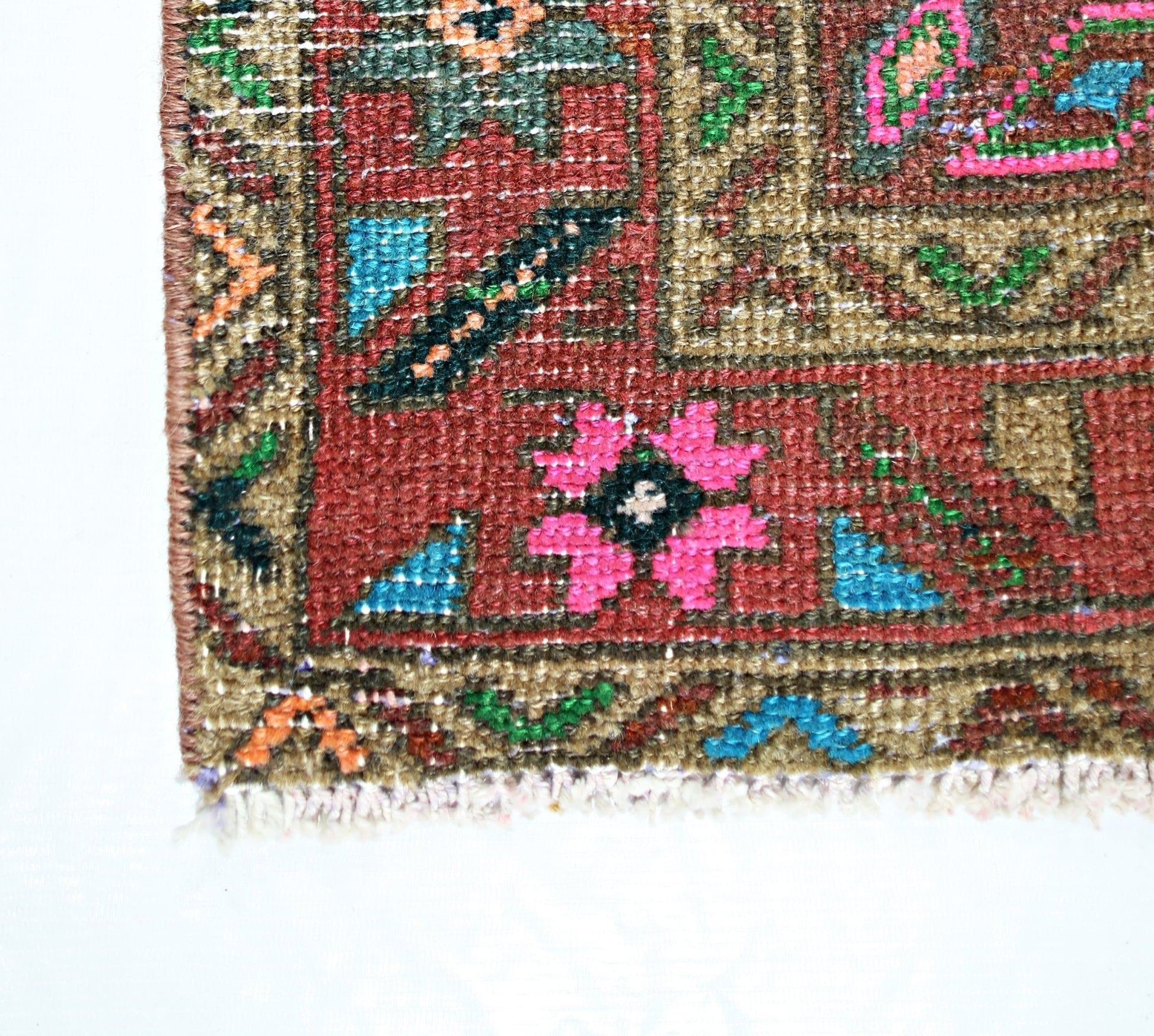 A close-up of a vintage Persian runner featuring a geometric floral pattern in vibrant colors.