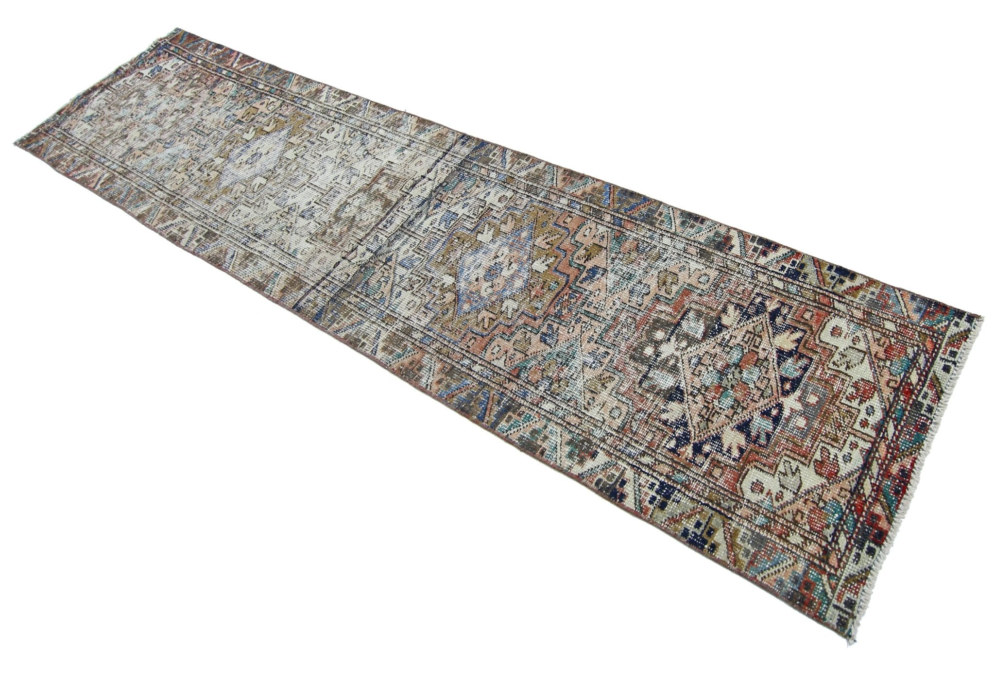 A vintage handmade Persian runner rug featuring a faded geometric pattern in muted earth tones.