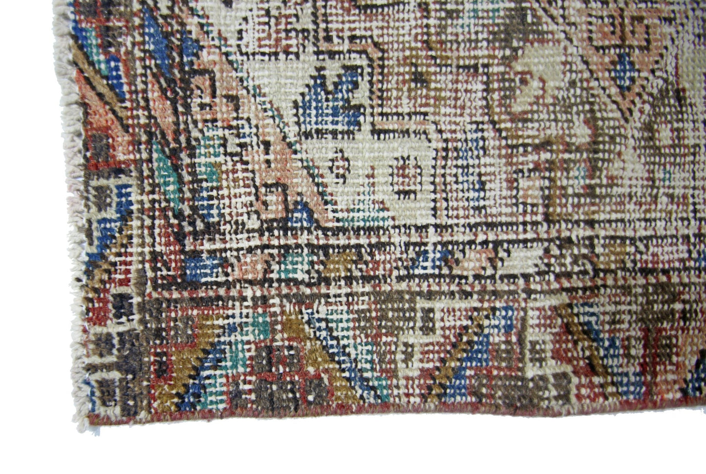 A close-up of a vintage Persian runner featuring a faded geometric pattern in wool on cotton.