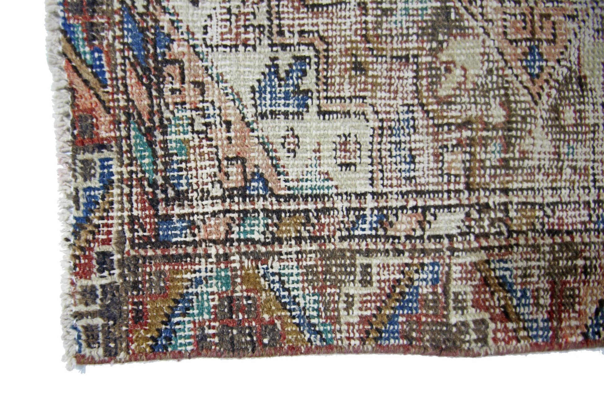 A close-up of a vintage Persian runner featuring a faded geometric pattern in wool on cotton.