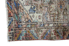 A close-up of a vintage Persian runner featuring a faded geometric pattern in wool on cotton.