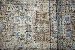 A vintage Persian runner featuring a geometric pattern in muted blue, brown, and cream tones.