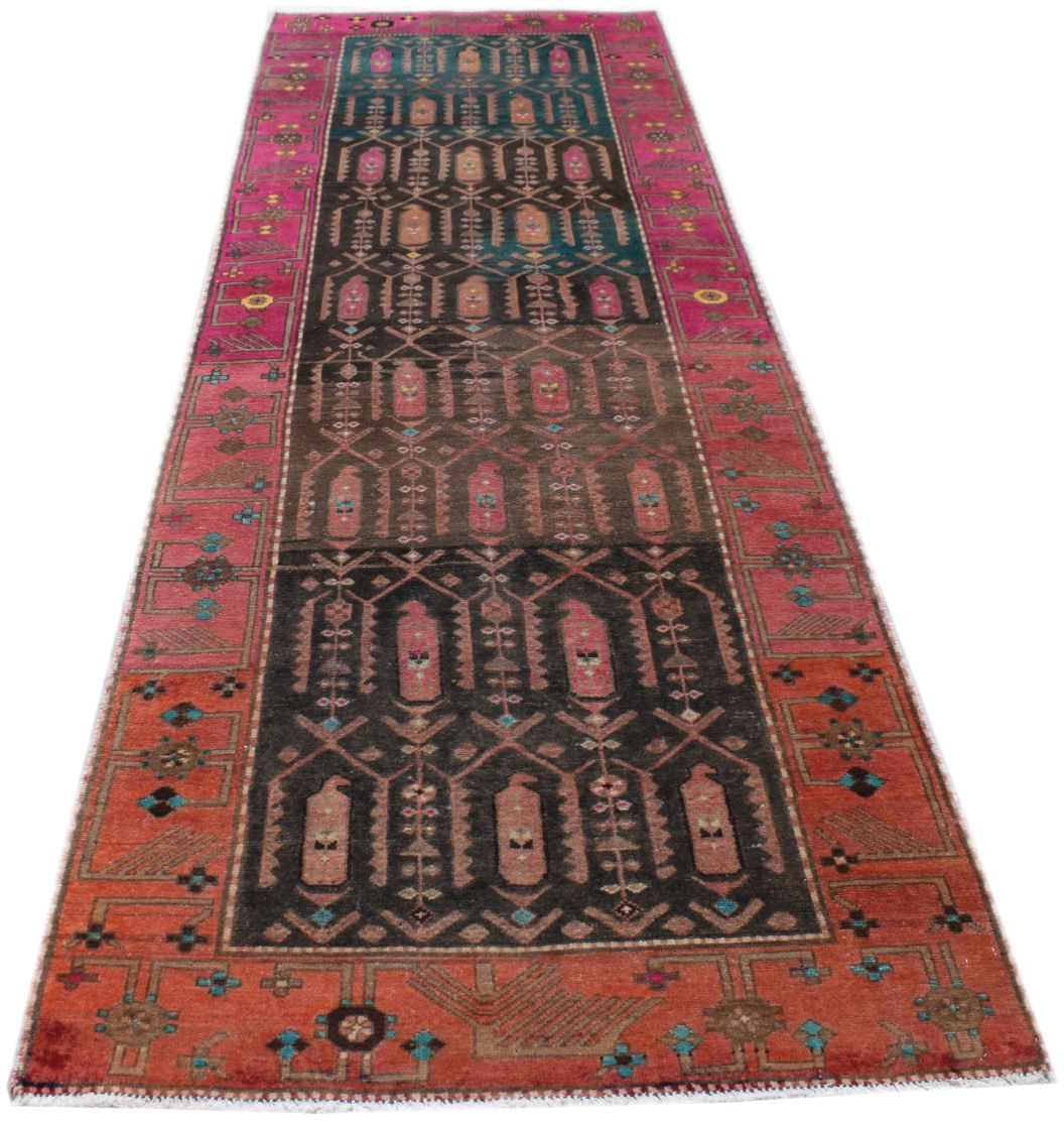 A handmade vintage Persian runner rug featuring a dark central field with geometric tribal motifs.