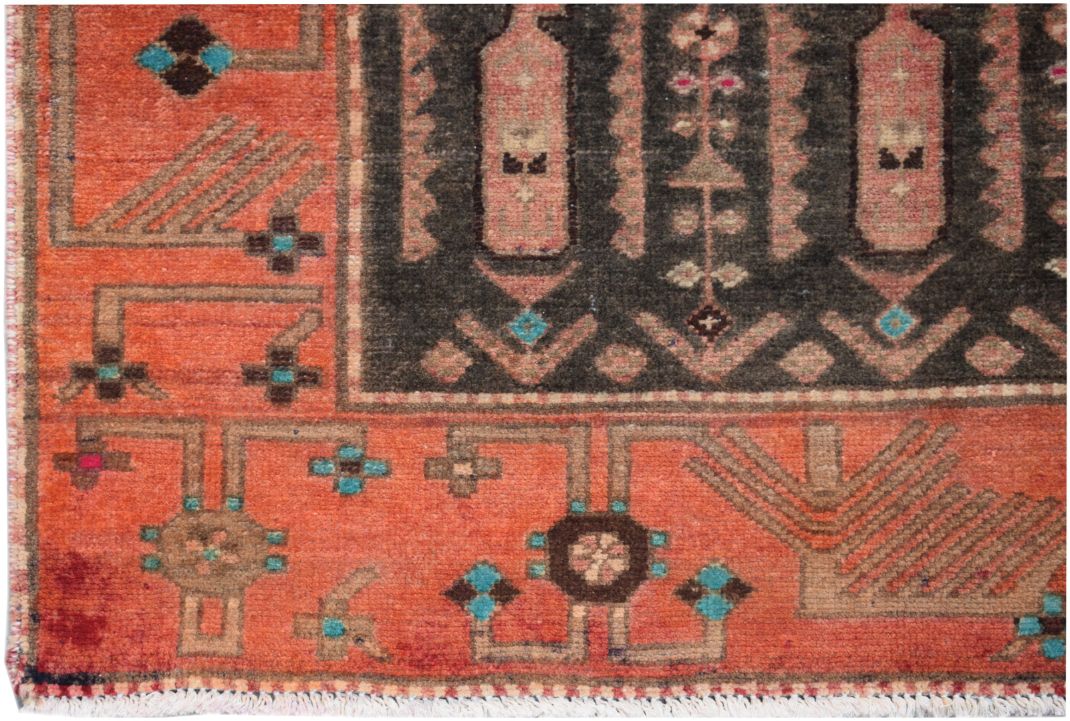 A vintage Persian runner featuring a geometric tribal pattern in orange, black, and blue wool.
