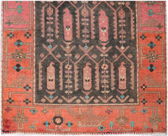 A vintage Persian runner featuring a dark central field with pink motifs and orange borders.