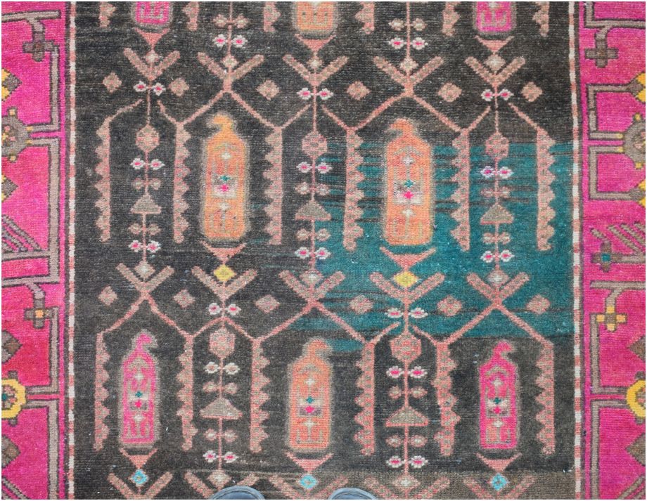 A vintage Persian runner featuring a dark field with geometric motifs and vibrant pink borders.