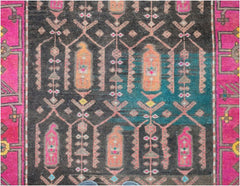 A vintage Persian runner featuring a dark field with geometric motifs and vibrant pink borders.