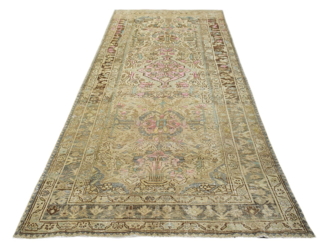 A vintage handwoven Persian runner featuring a faded floral pattern in muted earth tones and pink.