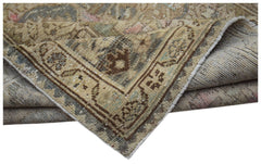 A handwoven vintage Persian runner featuring a faded floral pattern in muted earth tones.
