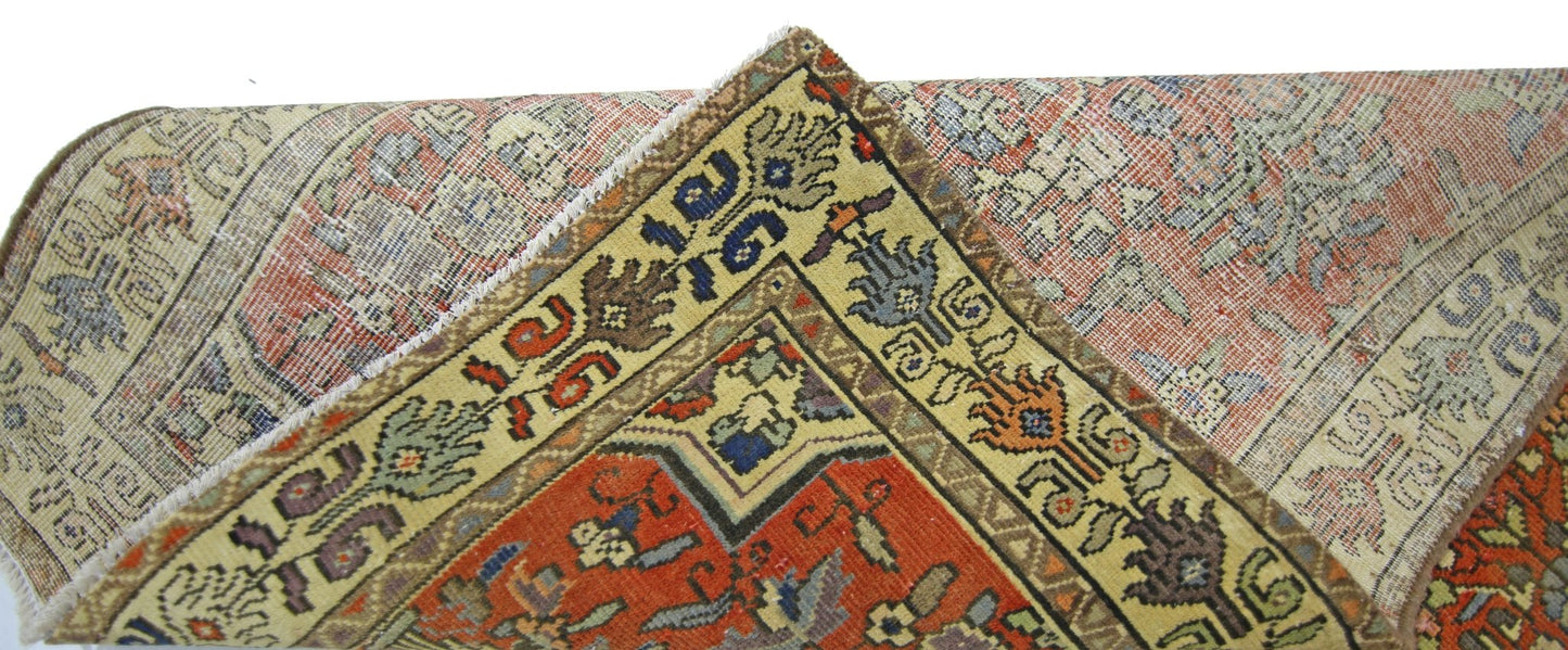 A corner view of a vintage Persian runner featuring intricate geometric patterns in red and yellow.