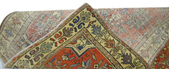 A corner view of a vintage Persian runner featuring intricate geometric patterns in red and yellow.