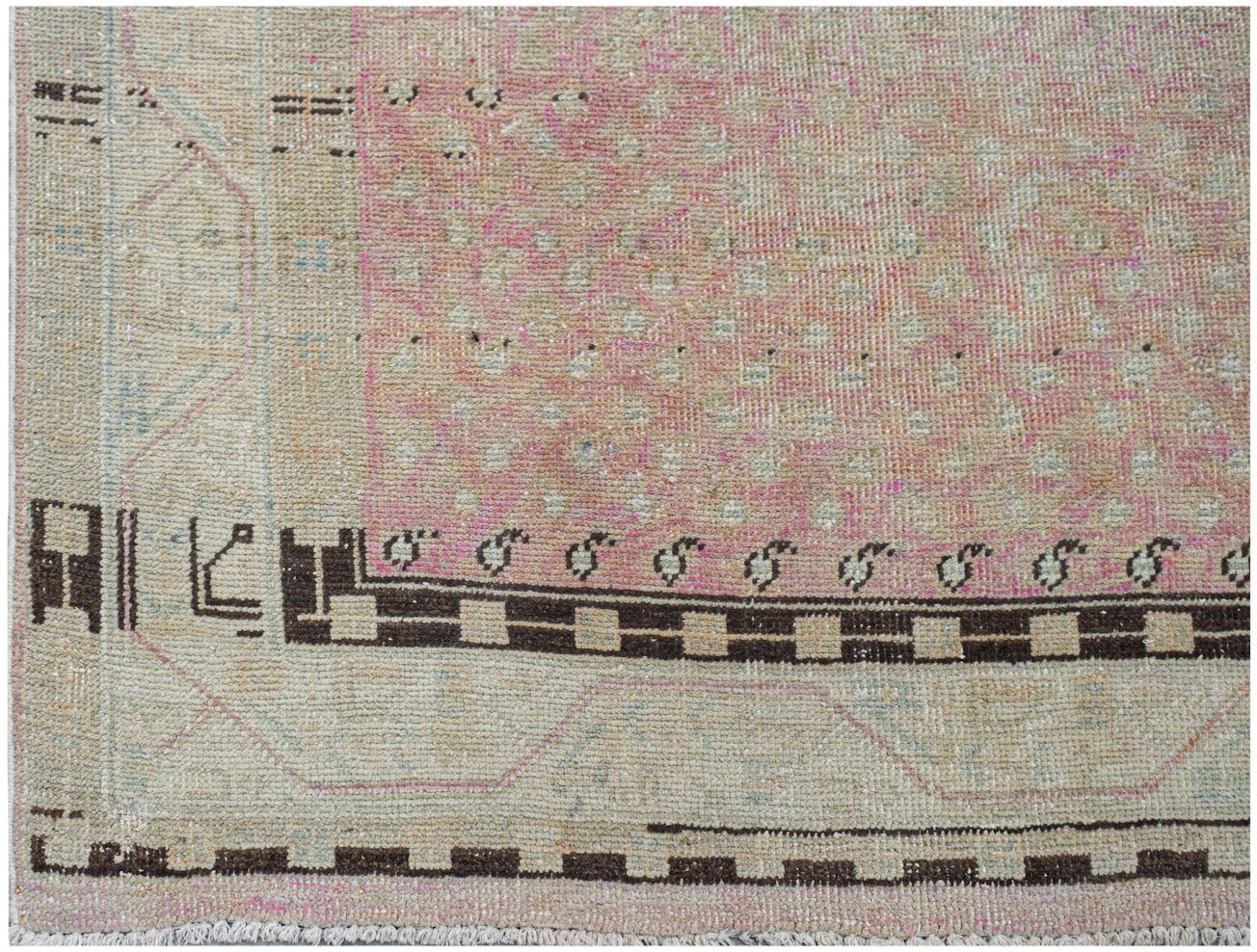 A vintage Persian runner featuring a faded pink field with geometric borders and wool pile.