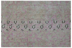 A vintage Persian runner featuring a faded beige and pink field with a dark geometric border.
