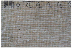 A close-up of a vintage Persian runner featuring a beige wool pile with a dark patterned border.