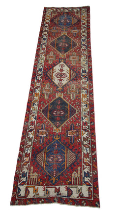 A vintage handmade Persian runner featuring geometric medallions on a red wool field.