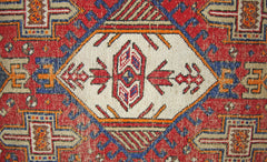 A vintage Persian runner featuring a geometric white central medallion on a red and blue field.