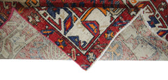 A folded vintage Persian runner featuring a geometric pattern in red, blue, and cream wool.