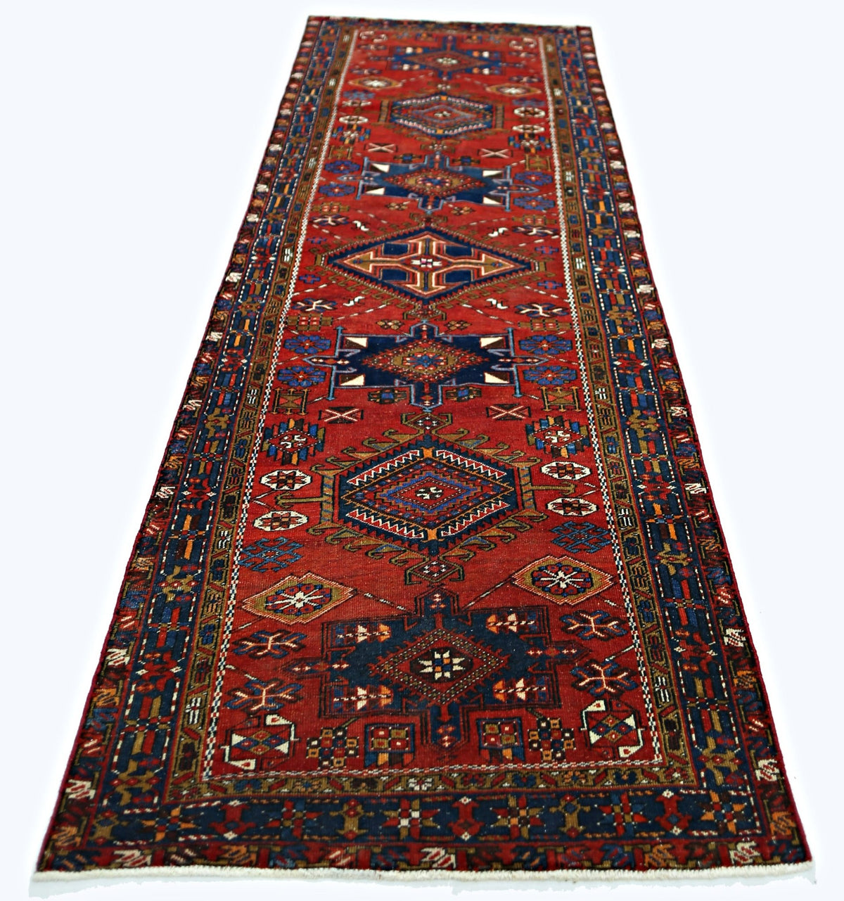 A vintage Persian runner featuring geometric patterns in red, blue, and cream wool.