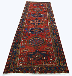 A vintage Persian runner featuring geometric patterns in red, blue, and cream wool.