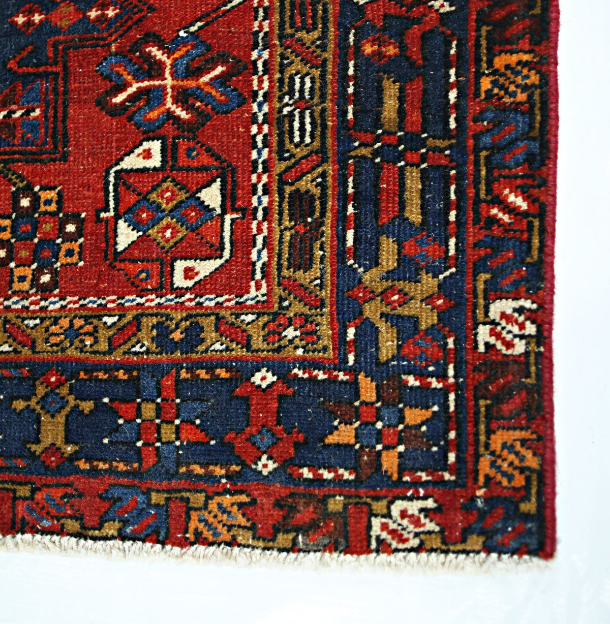A vintage Persian runner featuring a geometric pattern in red, blue, and gold wool.