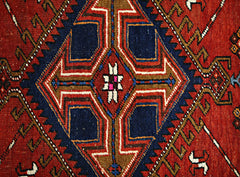 A vintage Persian runner featuring a geometric diamond medallion in red, blue, and brown wool.