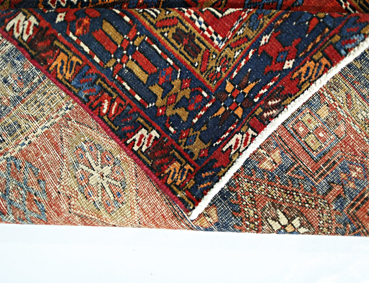 A folded vintage Persian runner featuring intricate geometric patterns in red, blue, and tan.