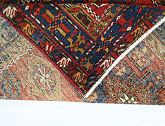 A folded vintage Persian runner featuring intricate geometric patterns in red, blue, and tan.