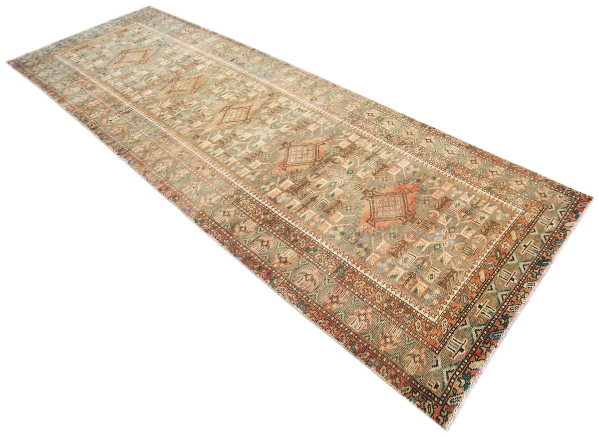 A vintage handmade Persian runner rug featuring intricate geometric patterns in muted earth tones.