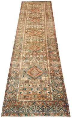 A vintage Persian runner rug featuring geometric patterns in muted earth tones and blue accents.