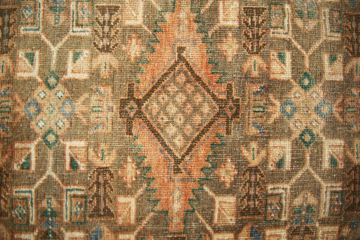 A vintage Persian runner featuring a geometric diamond pattern in earthy tones.