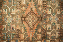 A vintage Persian runner featuring a geometric diamond pattern in earthy tones.