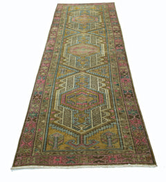 A vintage Persian runner rug featuring geometric patterns in shades of pink, blue, and gold.