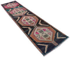 A handmade vintage Persian runner featuring geometric medallions in pink, green, and orange.