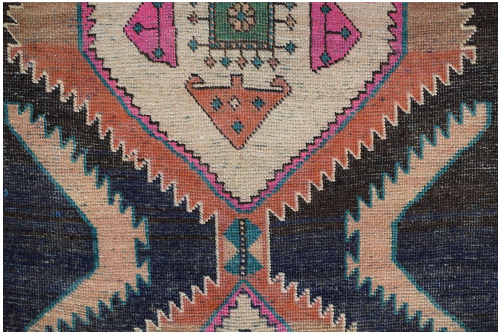 A vintage Persian runner featuring a geometric tribal pattern in shades of blue, pink, and orange.